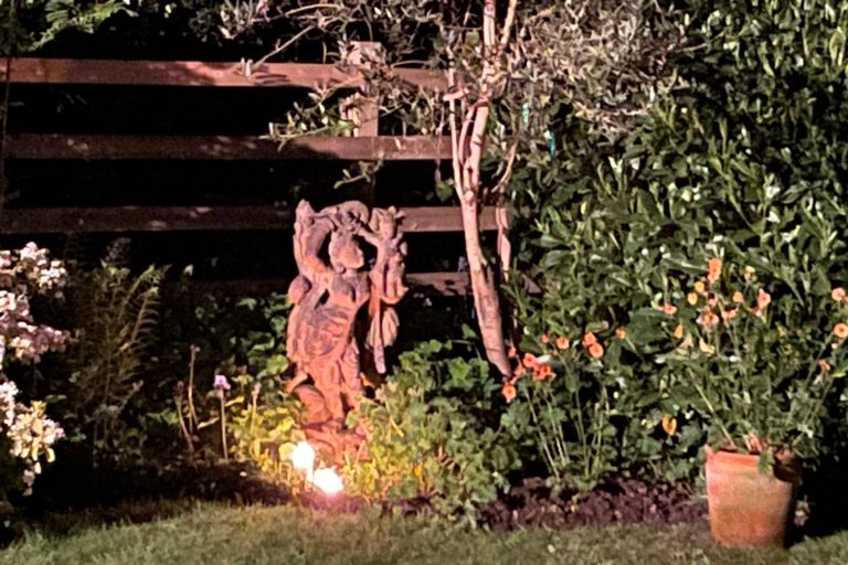 candles burning infront of garden shrine.